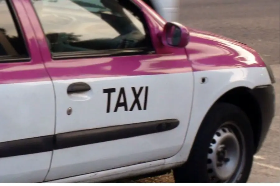 Pink and white taxi on the road