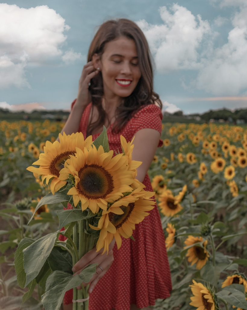 Smiling while holding a bouquet of sunflowers on a sunny day at The Berry Farms sunflower field