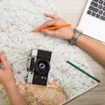 Traveling hacks photo of someone planning a trip with a map and laptop.