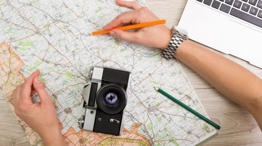 Traveling hacks photo of someone planning a trip with a map and laptop.