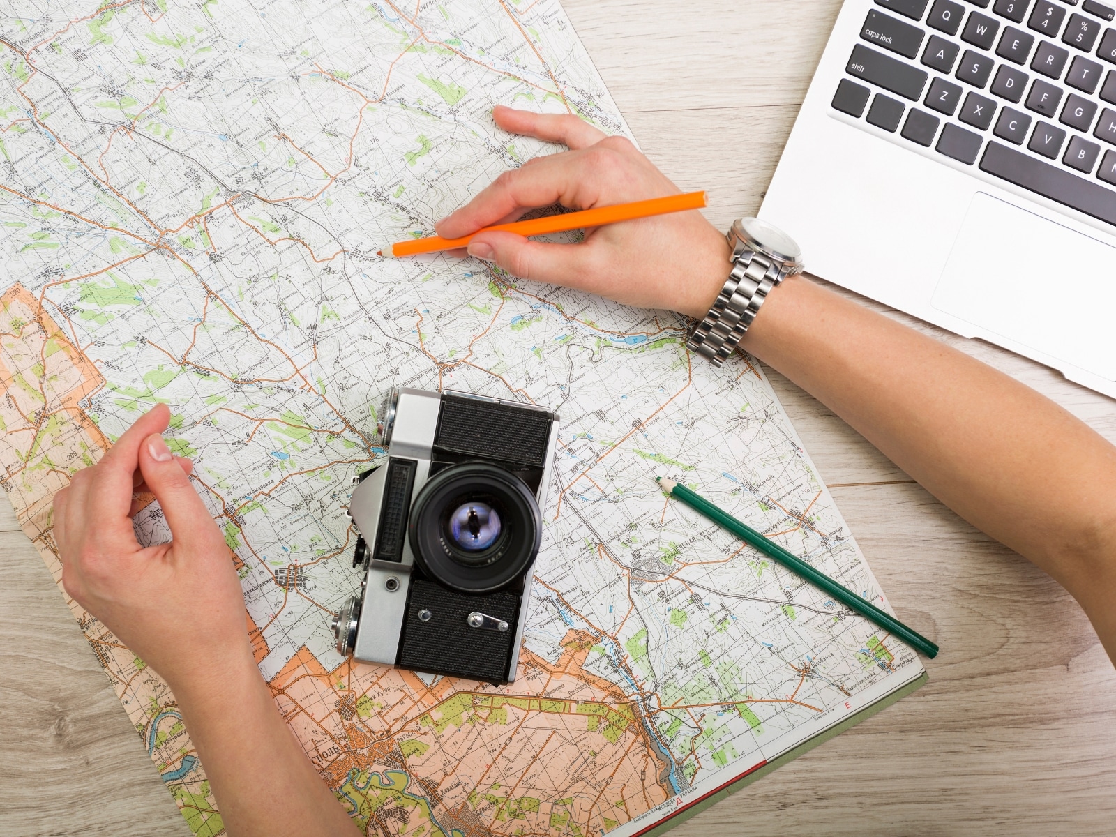 Traveling hacks photo of someone planning a trip with a map and laptop.