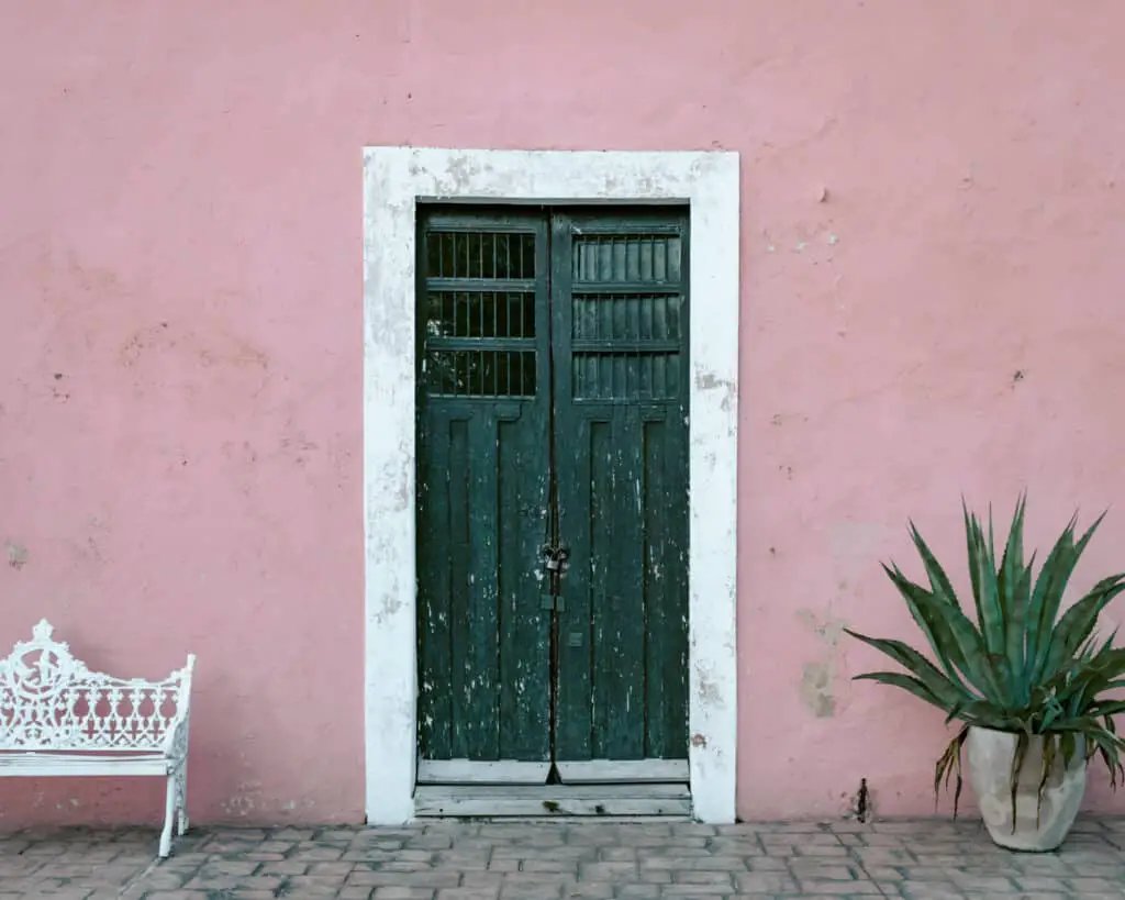 Picture of a pink building and green door in on Calzada De Los Frailes one of the top things to do in Valladolid.