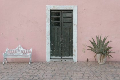 Picture of a pink building and green door in on Calzada De Los Frailes one of the top things to do in Valladolid.