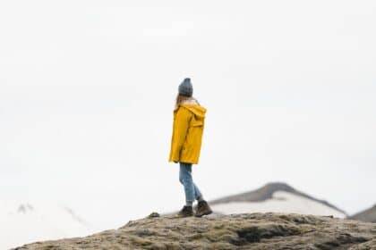 Traveling alone quotes photo of a woman standing on a mountain alone.