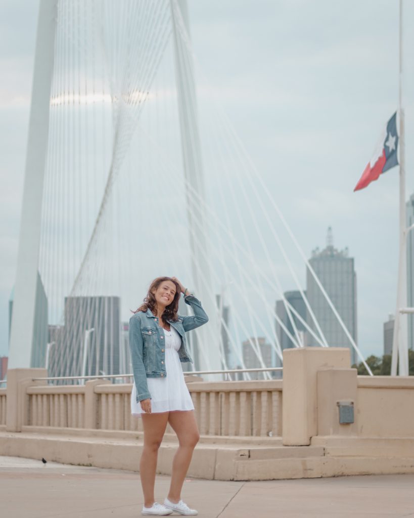 Me posing in front of the Dallas skyline and Margaret Hunt Hill Bridge one of the best places to take pictures in Dallas.