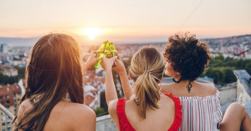 Rooftop captions photo of friends giving a cheers from a rooftop. 