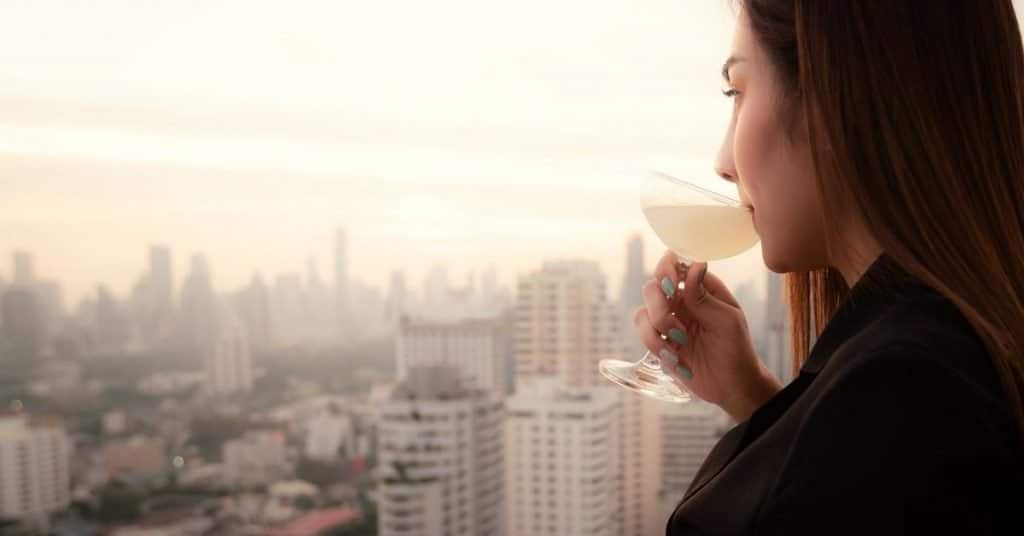 Rooftop captions photo of a woman having a cocktail admiring the New York City skyline. 