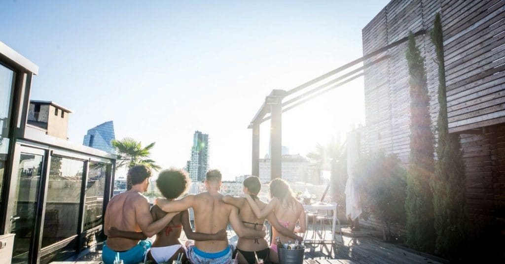 Rooftop quotes for Instagram captions photo of friends looking at the skyline from a rooftop pool.