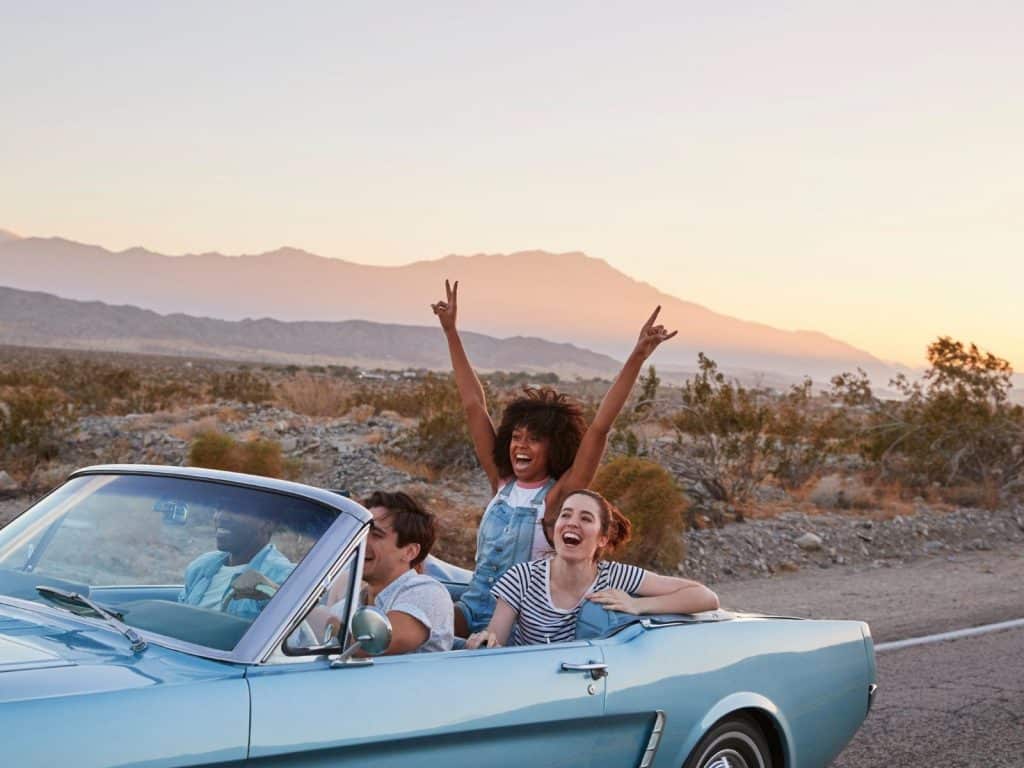 Road trip Instagram captions photo of friends in a car in the desert. 