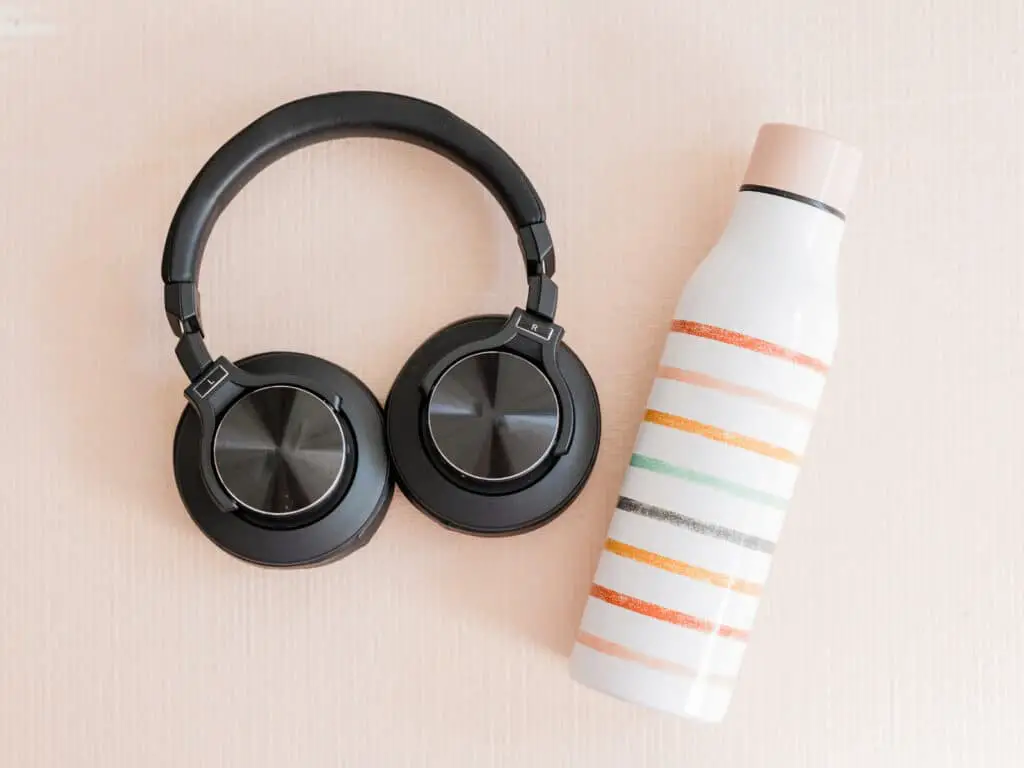 Take care of your skin while traveling photo of a water bottle and headphones. 