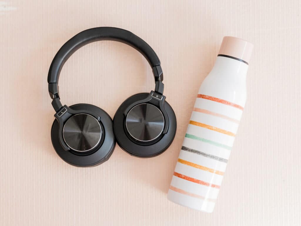 Take care of your skin while traveling photo of a water bottle and headphones.