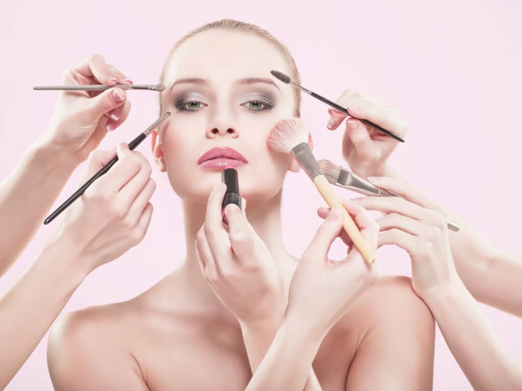 Take care of your skin while traveling photo of a woman wearing too much make and putting on more.