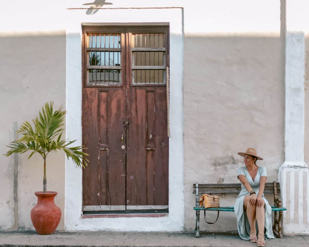 Me posing on a bench by a rustic building on Calzada De Los Frailes  in Valladolid. One of the best things to do in Valladolid. 