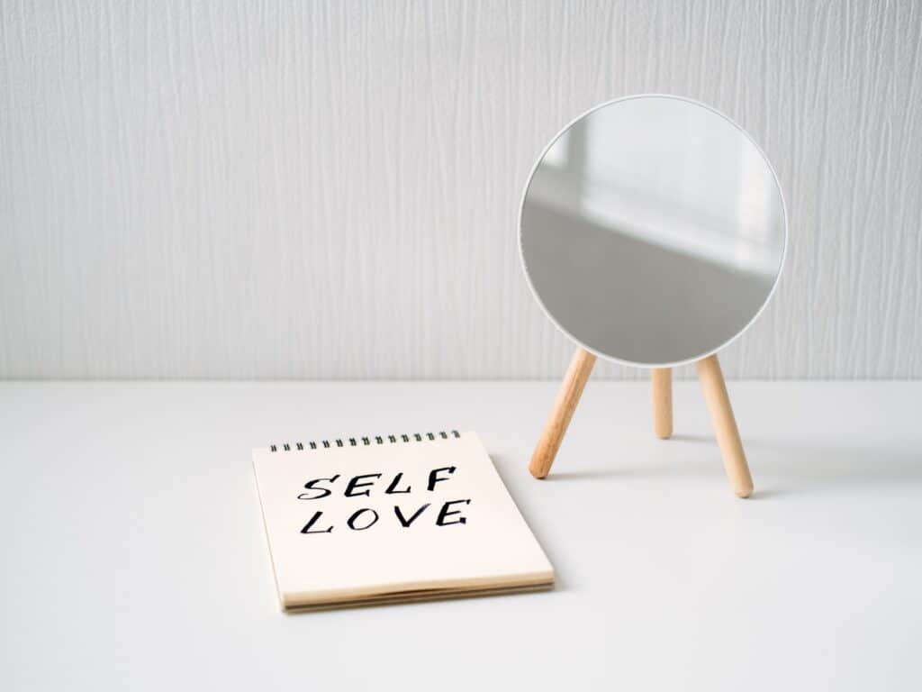 Self love quotes for Instagram photo of a mirror and a notepad that says self love. 