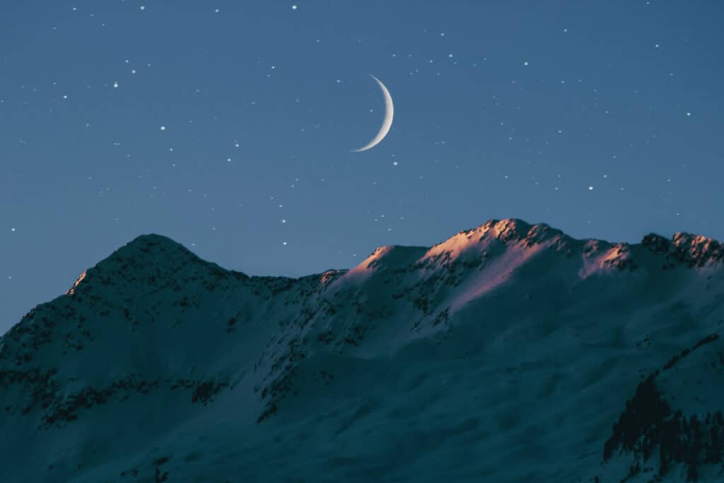 Moon and star Instagram quotes photo of a crescent moon and stars with snow capped mountains. 