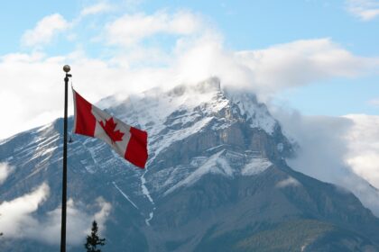 Canada Instagram captions photo of the Canadian flag in front of a snow-capped mountain